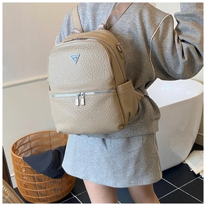 Sac à dos en cuir beige grainé avec logo métallique porté par un mannequin