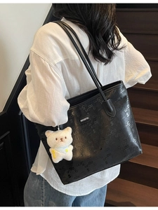 Black large capacity tote bag with embossed numbers and a white teddy bear charm