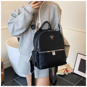 Détail d'un sac à dos noir en cuir texturé avec logo triangulaire et poches multiples