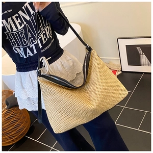 Détail du sac cabas en paille tissée avec lanières en cuir noir et fermeture éclair