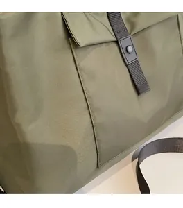 Detail of army green nylon travel bag showing snap button strap and fabric texture