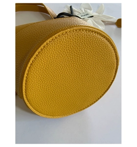 Detailed view of the round bottom and stitching on a yellow lychee leather bucket bag