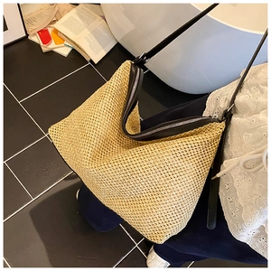 Détail de la texture tressée en paille et de la bordure en cuir noir du sac hobo