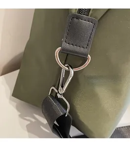 Detail of silver metal lobster clasp and D-ring on olive green nylon travel bag