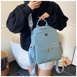 Détail du sac à dos en cuir grainé bleu clair avec logo triangulaire et large sangle à motifs