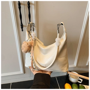 Detail of cream croc-effect hobo bag with large decorative beads and plush bear charm