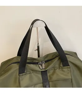 Detail of army green travel bag showing reinforced nylon handles and dual metal zippers