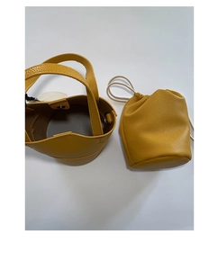 Detail view of yellow lychee pattern leather bucket bag with drawstring inner pouch