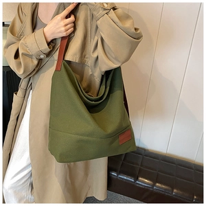 Olive green canvas hobo tote bag with brown leather straps shown on a model
