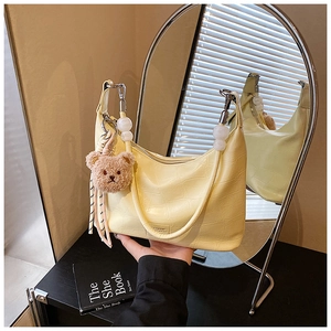 Close-up of yellow crocodile embossed faux leather bag with cute teddy bear charm