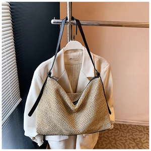 Détail de la texture du sac cabas en paille tissée et fine bandoulière en cuir noir