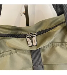 Close-up of smooth silver metal zippers on durable green nylon travel bag detail