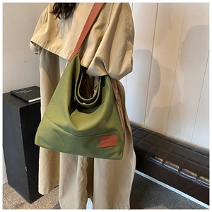 Detail of green canvas tote with leather shoulder strap and vintage stitched patch