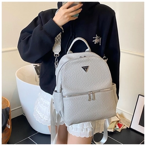 Détail du sac à dos en cuir grainé gris clair avec logo triangulaire métallique