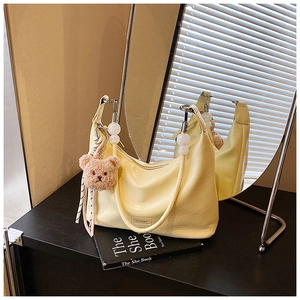 Detail of yellow crocodile pattern bag with plush bear charm and beaded chain strap