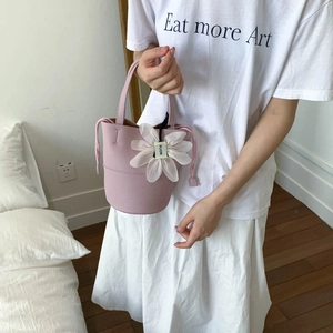 Detail of pink bucket bag featuring lychee grain PU leather and a floral charm ornament