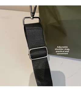 Detail of adjustable black fabric shoulder strap with silver metal buckles on a green bag