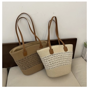 Detail of woven straw tote bag with intricate mesh hollow pattern and leather straps