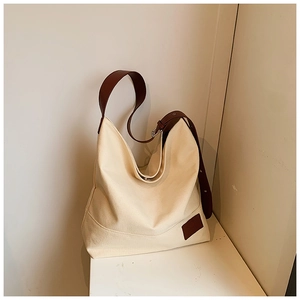 Close-up of beige canvas tote bag with brown leather strap and adjustable metal buckle