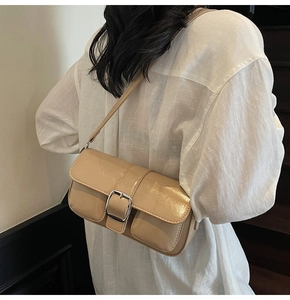 Close-up of stylish apricot patent leather shoulder bag with silver square buckle