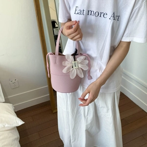 Detail of pink bucket bag with drawstring closure and white floral decorative charm