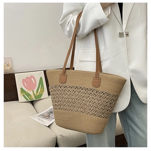 Detailed straw tote bag showing hollow weave texture and brown faux leather handle