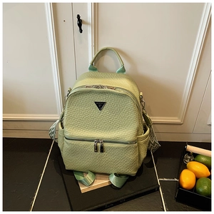 Gros plan détaillé du sac à dos vert clair texturé avec plaque logo métallique chic