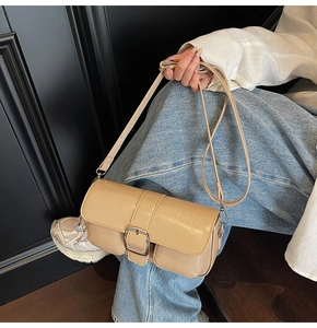 Detailed view of a beige patent leather crossbody bag with elegant silver buckle detail