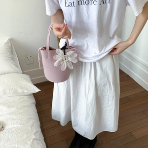 Detailed shot of pink textured leather bucket bag with large white silk flower charm