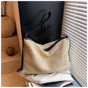 Détails de la texture en paille tressée et finitions en cuir noir d'un grand cabas