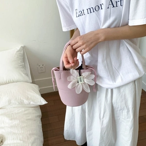 Close-up of pink pebbled leather bucket bag with a delicate white silk daisy charm