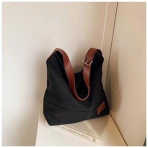 Detail of adjustable brown leather shoulder strap on a black canvas tote bag