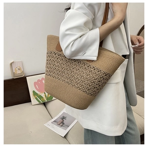 Detail of hollow woven straw tote bag with brown leather handles and large capacity