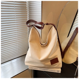 Detail showing adjustable brown leather strap and metal buckle on beige canvas tote bag