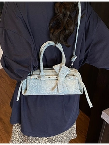 Blue denim pillow bag featuring a large bow and silver studs with an adjustable strap