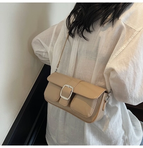 Detail view of beige rectangular crossbody bag with large silver metal square buckle buckle