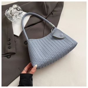 Close-up of light blue woven leather shoulder bag showing intricate texture and snap closure