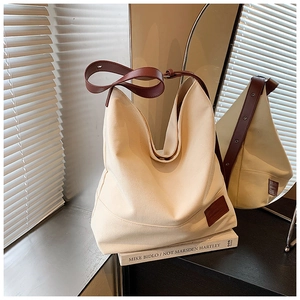 Detail of canvas tote bag with brown PU strap and leather logo tag in natural light
