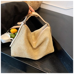 Détails du tissage d'un sac hobo en paille beige avec une bandoulière en similicuir