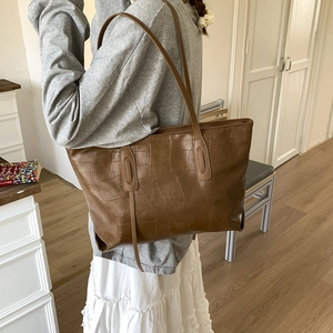 Close-up of brown crocodile pattern tote bag showing glossy leather texture and straps
