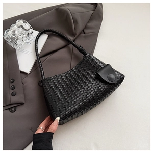Close-up of woven black hobo bag with textured pattern and braided leather shoulder strap