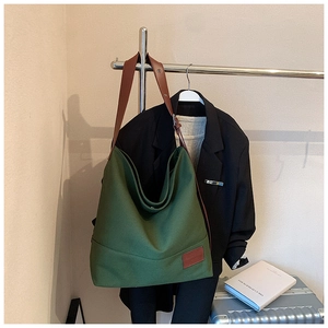 Close-up of army green canvas tote with brown leather strap hanging in a stylish setting