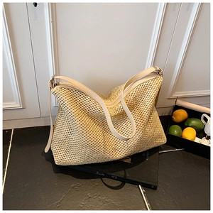 Close-up of beige woven tote bag showing detailed mesh texture and leather shoulder strap