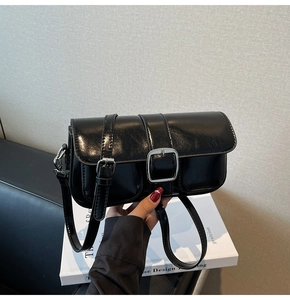 Detailed macro view of black glossy leather handbag with silver metallic buckle accents