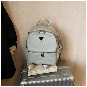 Gros plan d'un sac à dos en cuir gris avec logo triangle argenté et fermetures éclair
