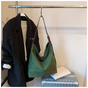 Detail of green canvas hobo bag featuring adjustable brown leather strap and metal buckle