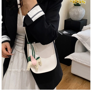 Detail of white lychee leather bucket bag featuring a cute horse charm on a model