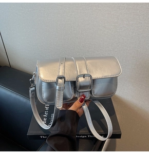 Detailed view of silver metallic underarm bag with sleek dual buckle strap accents