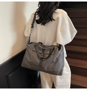 Detail of grey travel bag with buckle pocket and adjustable strap in lifestyle scene