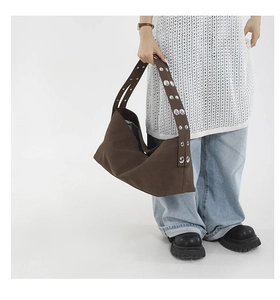 Detail of wide canvas strap with silver metal rivets on dark coffee crossbody bag
